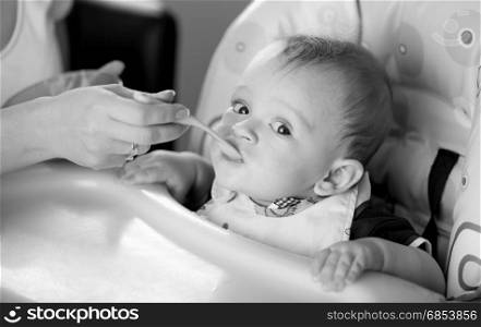 Black and white portrait of young mother feeding her baby