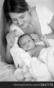 Black and white portrait of young mother posing with baby boy on bed