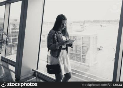 Black and white portrait of young woman using digital tablet at airport