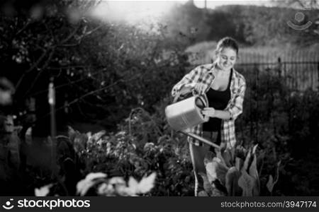 Black and white portrait of young woman working in garden and watering plants