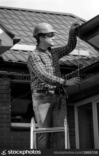 Black and white portrait of young worker repairing house roof