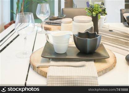 Black and white pottery cups setting on wooden cutting plate on dining table