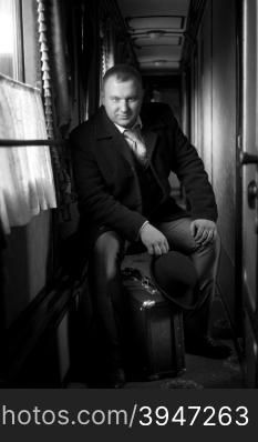 Black and white retro photo of man sitting in old train