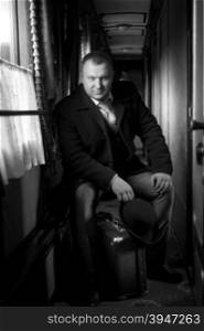 Black and white retro photo of man sitting in old train