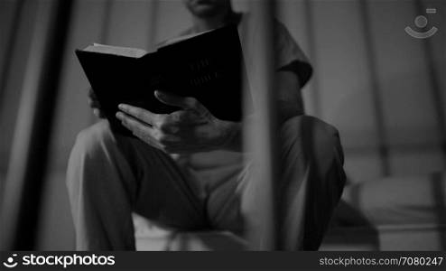 Black and white scene of a bible reading inmate in prison