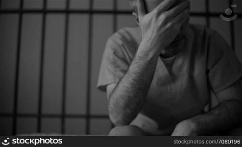 Black and white scene of a depressed inmate crying in prison