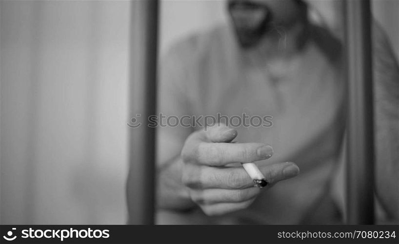 Black and white Scene of a depressed inmate smoking in prison