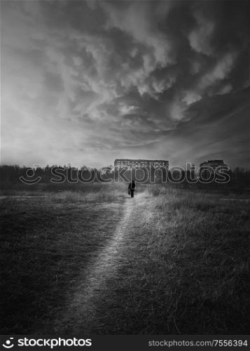 Black and white scene, vertical shot of a wanderer man silhouette walking narrow pathway throw the wilderness. Silent evening atmosphere, dramatic landscape, loneliness and solitude concept.