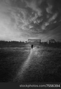 Black and white scene, vertical shot of a wanderer man silhouette walking narrow pathway throw the wilderness. Silent evening atmosphere, dramatic landscape, loneliness and solitude concept.