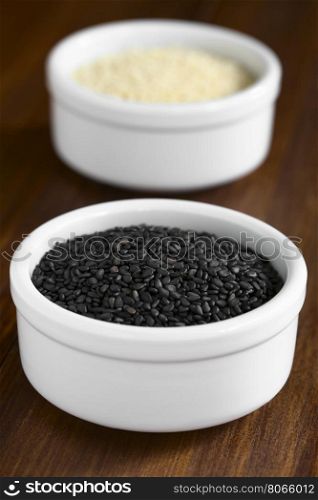Black and white sesame seeds in small bowls, photographed with natural light (Selective Focus, Focus in the middle of the black seeds)