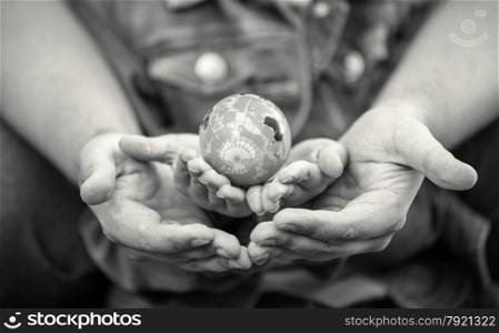 Black and white shot of man protecting girls hands holding globe