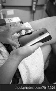 Black and white shot of woman sitting in airplane and typing text on smartphone