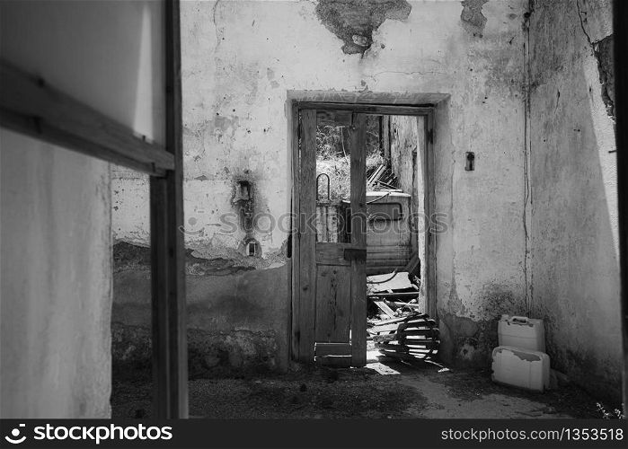 Black and white shot through a window in a deserted and rundown residential building on the island of Rhodes in Greece