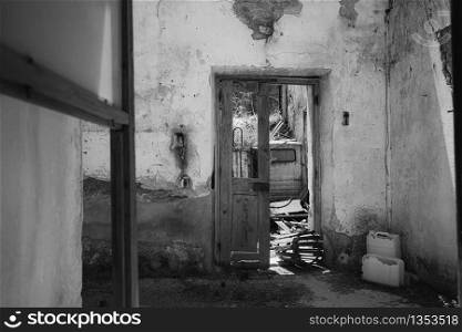 Black and white shot through a window in a deserted and rundown residential building on the island of Rhodes in Greece