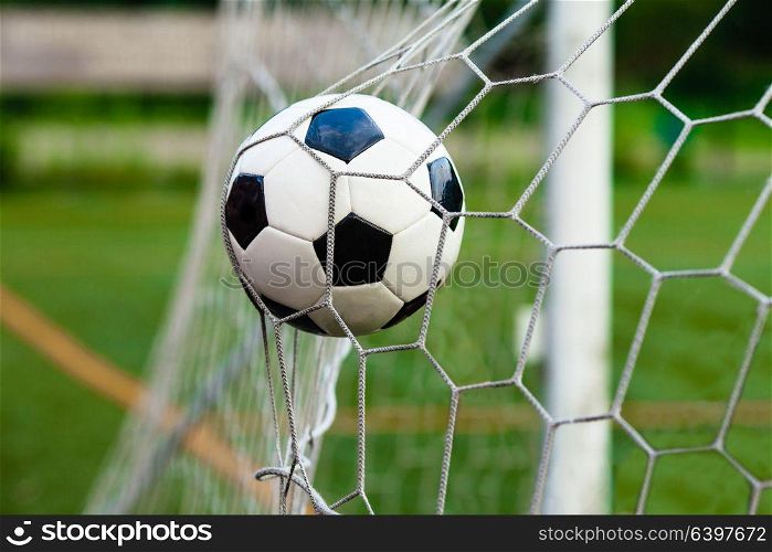 Black and white soccer ball in the gate. Concept of victory in the match. Soccer ball in goal