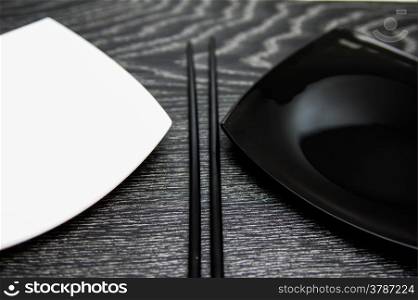 Black and white square plate with chopsticks on black table