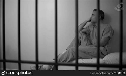 Black and white View of a sad inmate reclining on bed in prison