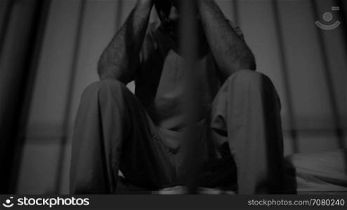 Black and white view of dramatic scene of a depressed inmate in jail
