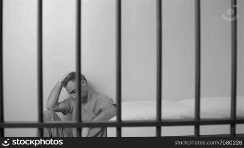 Black and white view of scene of a discouraged inmate in prison