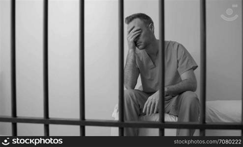 Black and white view of scene of a disheartened inmate in prison