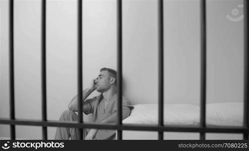 Black and white view of scene of a morose inmate in prison