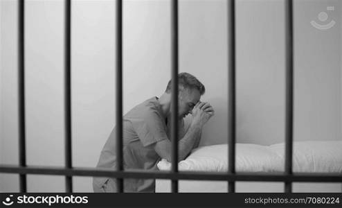 Black and white view of scene of a prayerful inmate in prison