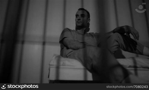 Black and white view of scene of a saddened inmate in prison