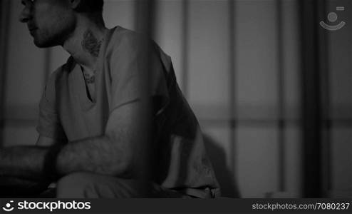 Black and white view of scene of a tattooed gang member in prison