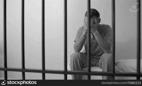 Black and white view of scene of an ashamed inmate in prison