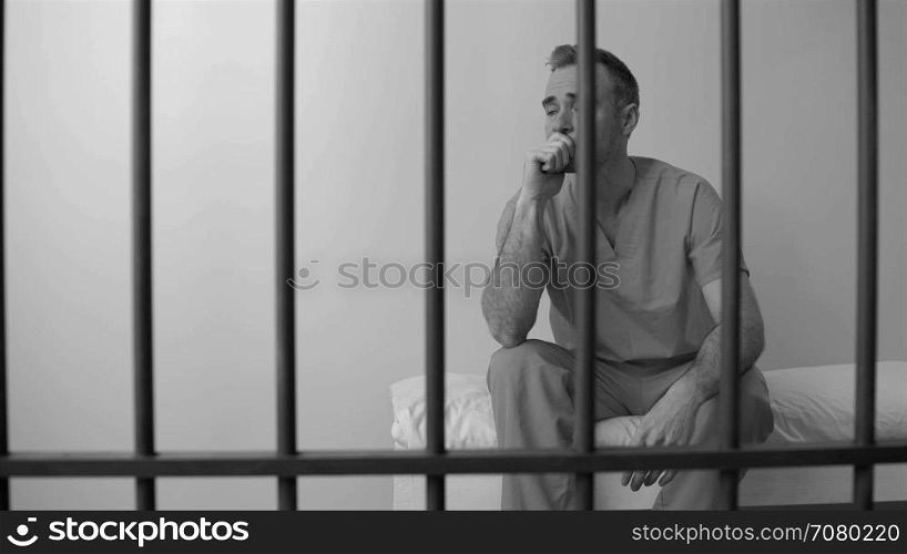 Black and white view of scene of an inmate in prison weeping