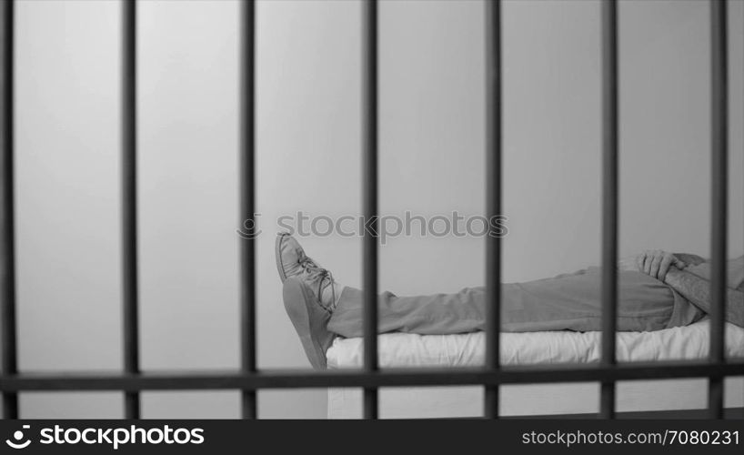 Black and white view of scene of an inmate sleeping in prison