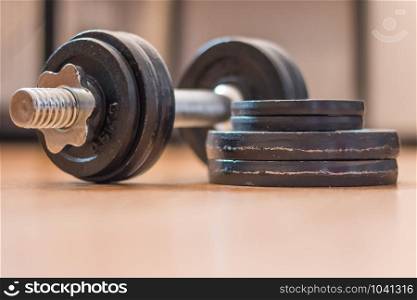Black bar bell on the wooden floor, physical exercise