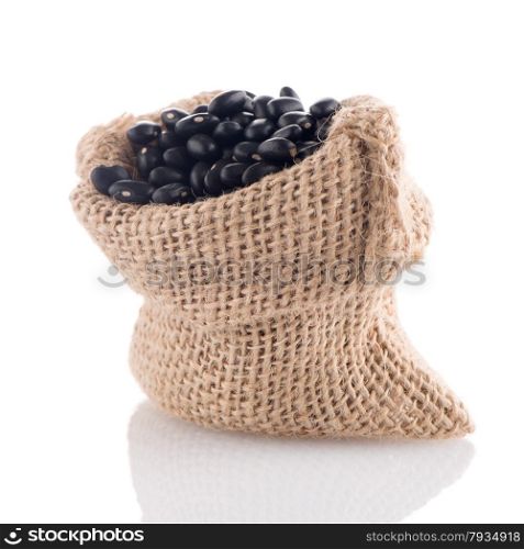 Black beans bag with wooden scoop on white background.