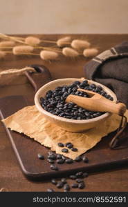 Black beans in a ceramic bowl on a rustic kitchen countertop.