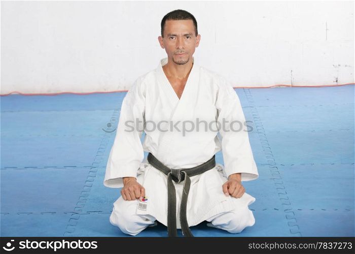Black Belt karate man sit on a position to start or finish practicing