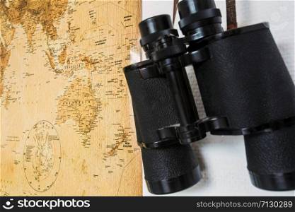 Black Binoculars and map hanging on a white wall, traveling concept closeup. Black Binoculars and map hanging on a white wall, traveling concept