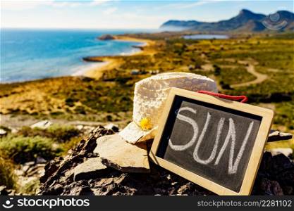 Black board with word sun against spanish sea coast. Landscape of Calblanque Park in Murcia Spain. Travel, vacation and prevention of vitamin D deficiency.. Black board with word sun against sea coast
