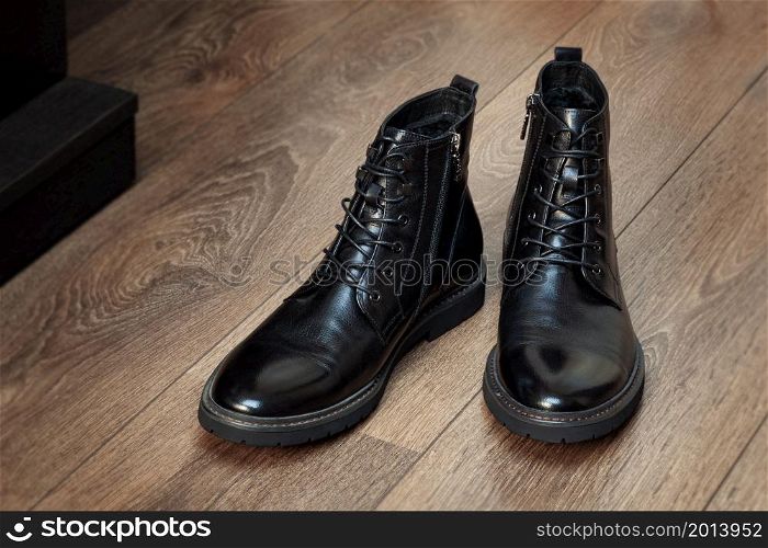 Black boots leather for men in the interior on a wooden floor isolated on white background