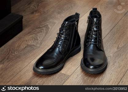 Black boots leather for men in the interior on a wooden floor isolated on white background