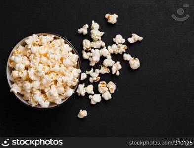 Black bowl with fresh salted popcorn on wooden background