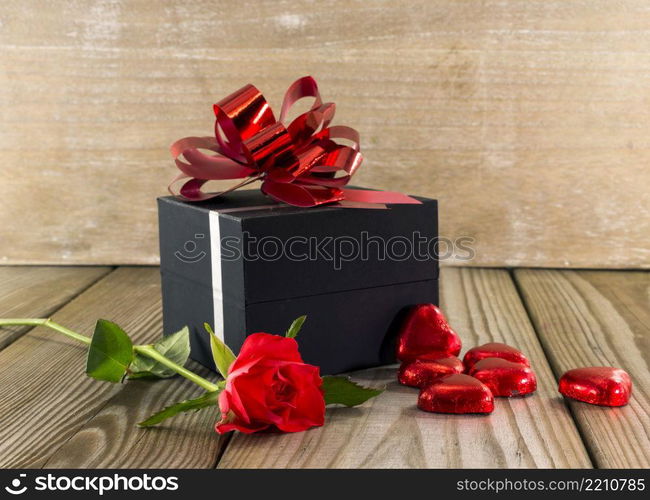 black box present with red rose and heart chocolate shapes. present for mothers day or valentines