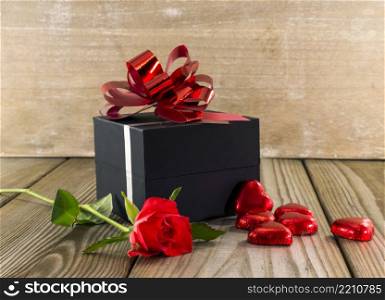 black box present with red rose and heart chocolate shapes. present for mothers day or valentines