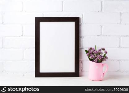 Black brown frame mockup with purple flowers in polka dot pink . Black brown frame mockup with purple field flowers in polka dot pink rustic pitcher vase. Empty frame mock up for presentation design. Template framing for modern art.