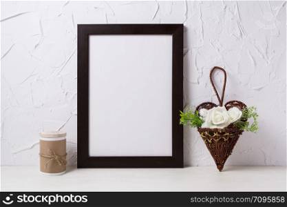 Black brown frame mockup with white roses in the wicker heart flower pot. Empty frame mock up for presentation design. Template framing for modern art.