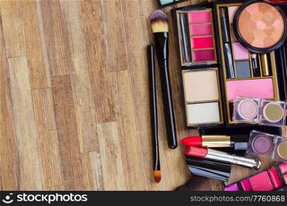 black brushes, lipsticks, maskara and eye shadows, copy space on wooden desktop. set of make up