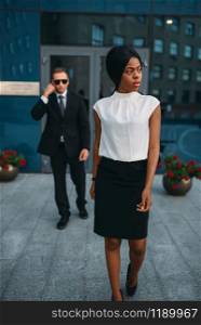 Black business woman bodyguard in suit and sunglasses on background. Security guard is a risky profession, protection of VIPs, guarding occupation, private safety