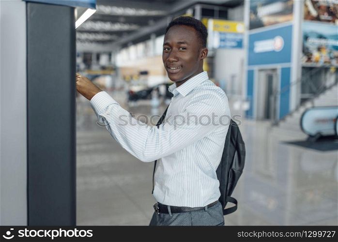 Black businessman at coffee machine in car dealership. Successful business person on motor show, black man in formal wear. Businessman at coffee machine in car dealership