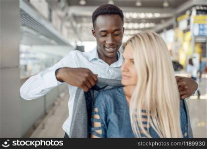 Black businessman takes care of a lady in car dealership. Successful business person on motor show, black man in formal wear, automobile showroom. Businessman takes care of a lady in car dealership