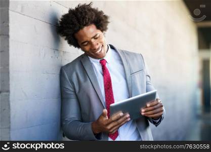 Black Businessman using a digital tablet in urban background. Man with afro hair.. Black Businessman using a digital tablet in urban background