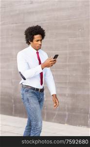 Black Businessman using his smartphone walking down the street.. Black Businessman using a smartphone near an office building